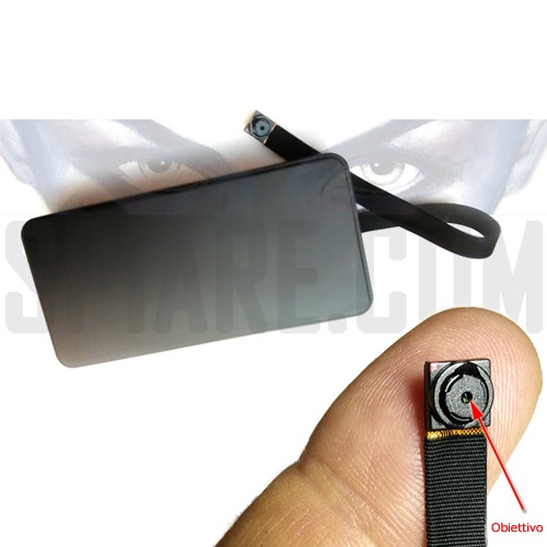 Microcamera a batteria con corpo centrale e obiettivo flat microscopico posizionato su un dito per evidenziarne le dimensioni