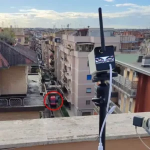 Telecamera con zoom montata su treppiede su un terrazzo per il monitoraggio a lunga distanza di una strada cittadina