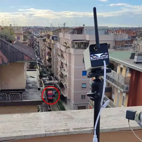 Telecamera con zoom montata su treppiede su un terrazzo per il monitoraggio a lunga distanza di una strada cittadina