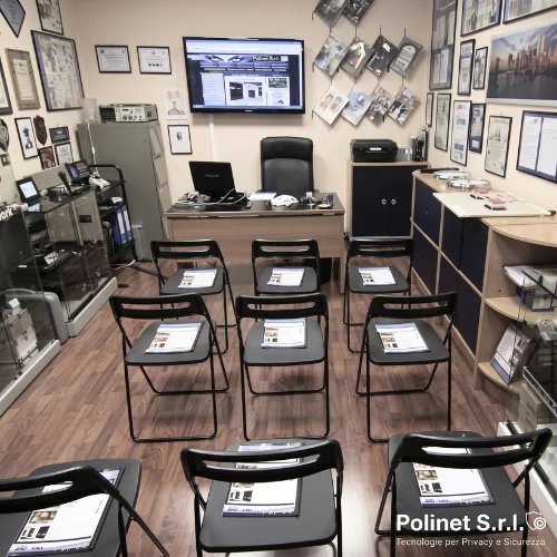 Aula corsi TSCM Polinet S.r.l. a Roma vista dall'ingresso con postazioni formative, vetrine attrezzate con strumentazione tecnica e pareti decorate con certificazioni e riconoscimenti professionali